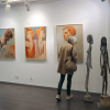 Ausstellungsbesucherin interessiert sich für Jolanta Switajskis Skulpturen und Hans Gunschs Gemälde