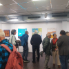 Ausstellungsbesucher beim Betrachten der Kunstwerke und im Gespräch